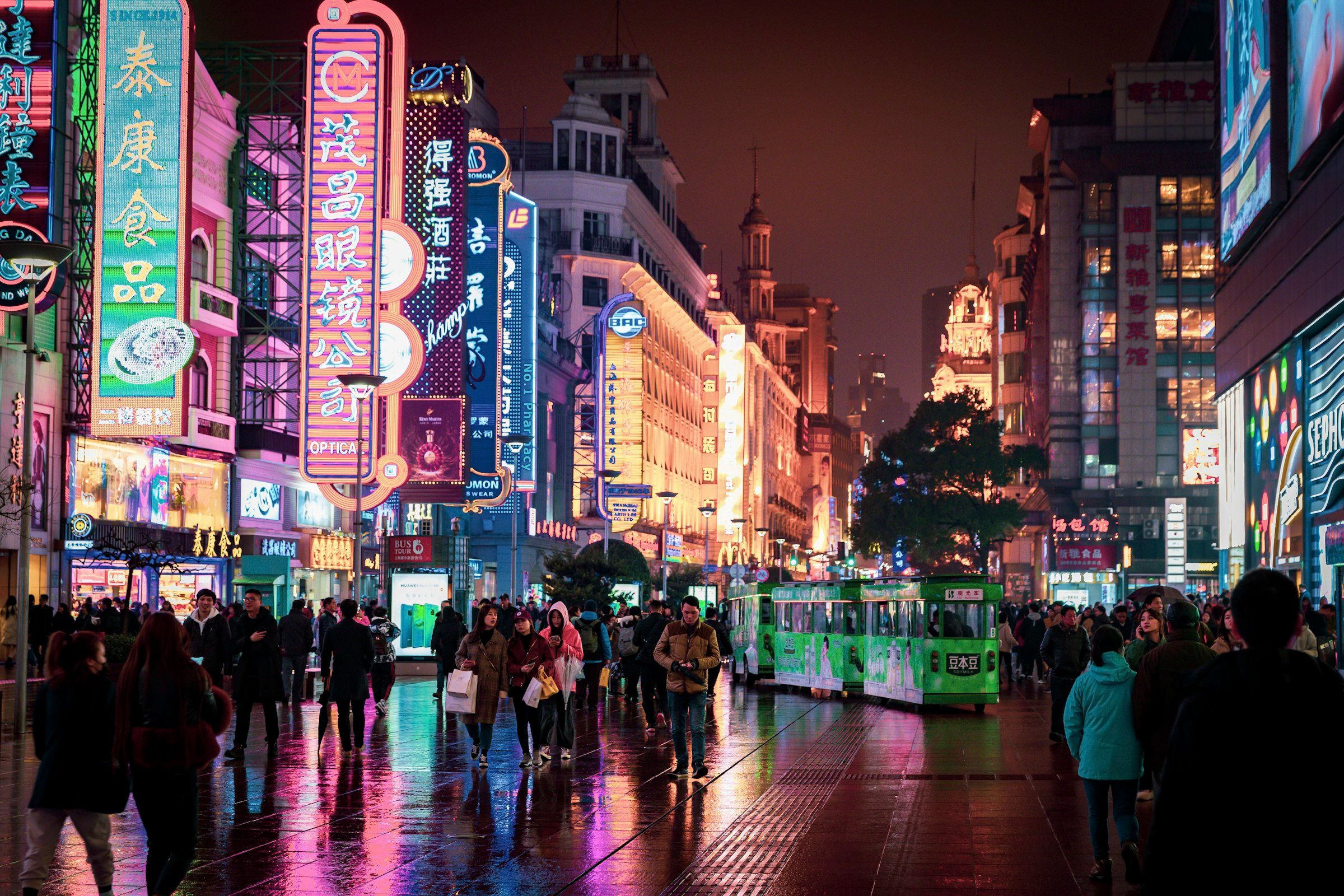 Shoppers on a neon-lit shopping street in Shanghai at night